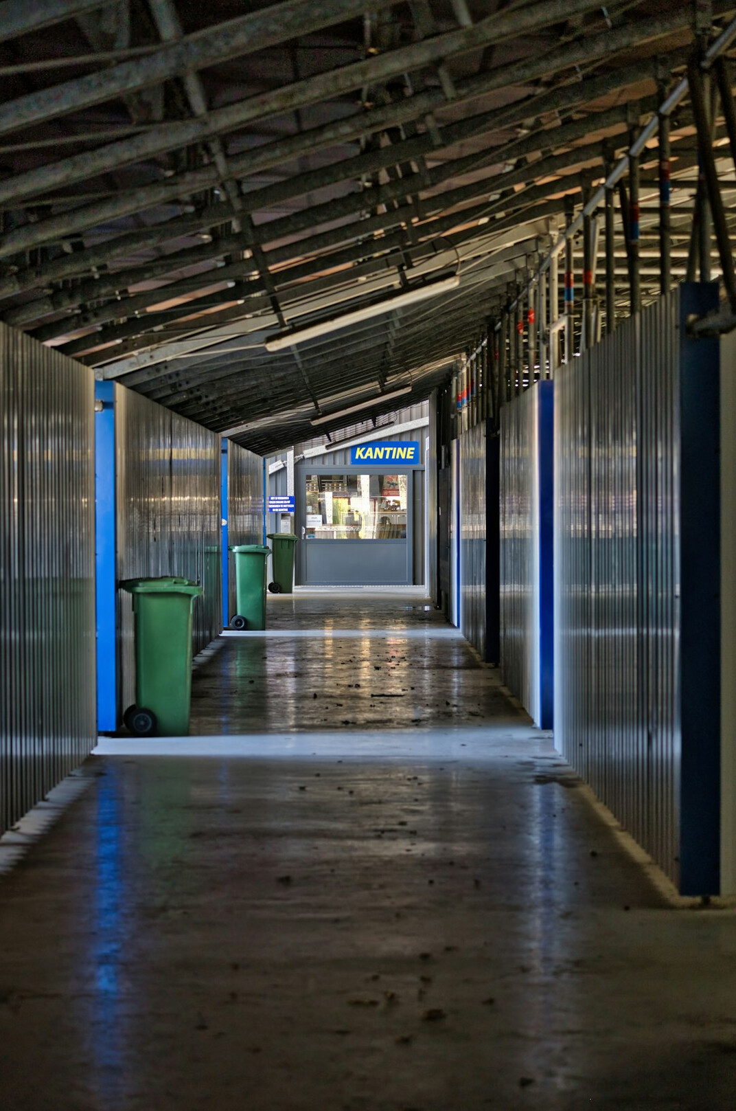 TV studio crew members walking through a backstage corridor with monitors